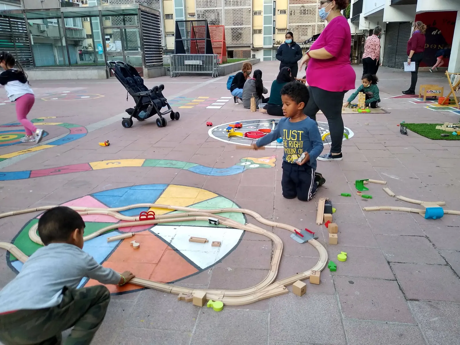 Infants jugant amb jocs educatius a una plaça del barri amb les monitores d'Ubuntu